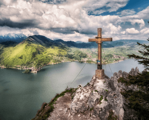 Mountain cross overlooking lake and green hills