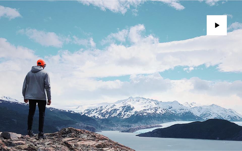 Person stands overlooking snowy mountains.