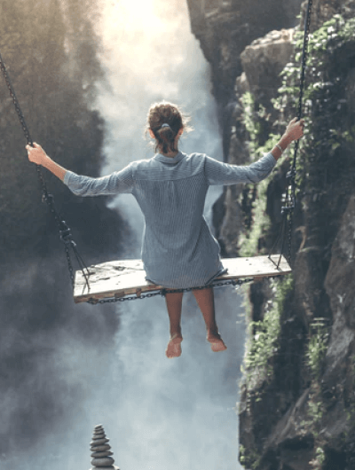 Person on swing above misty canyon view.