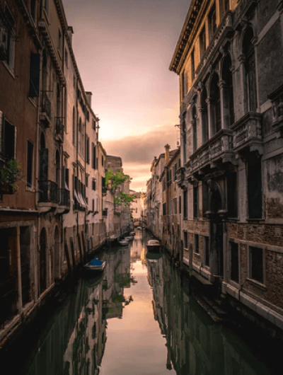 Venice canal at sunset with historic buildings reflected.