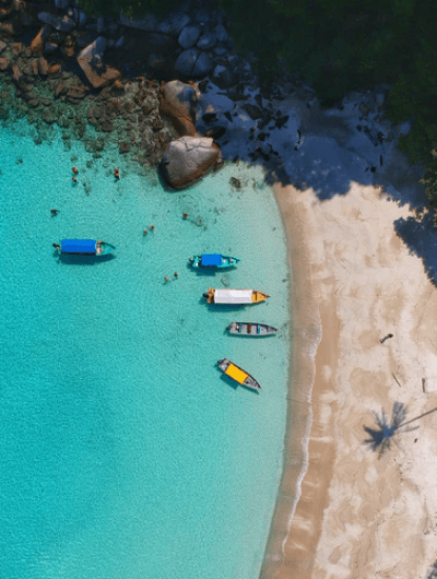 Aerial view of boats on turquoise beach shoreline.