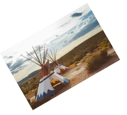 Teepees in desert under cloudy sky