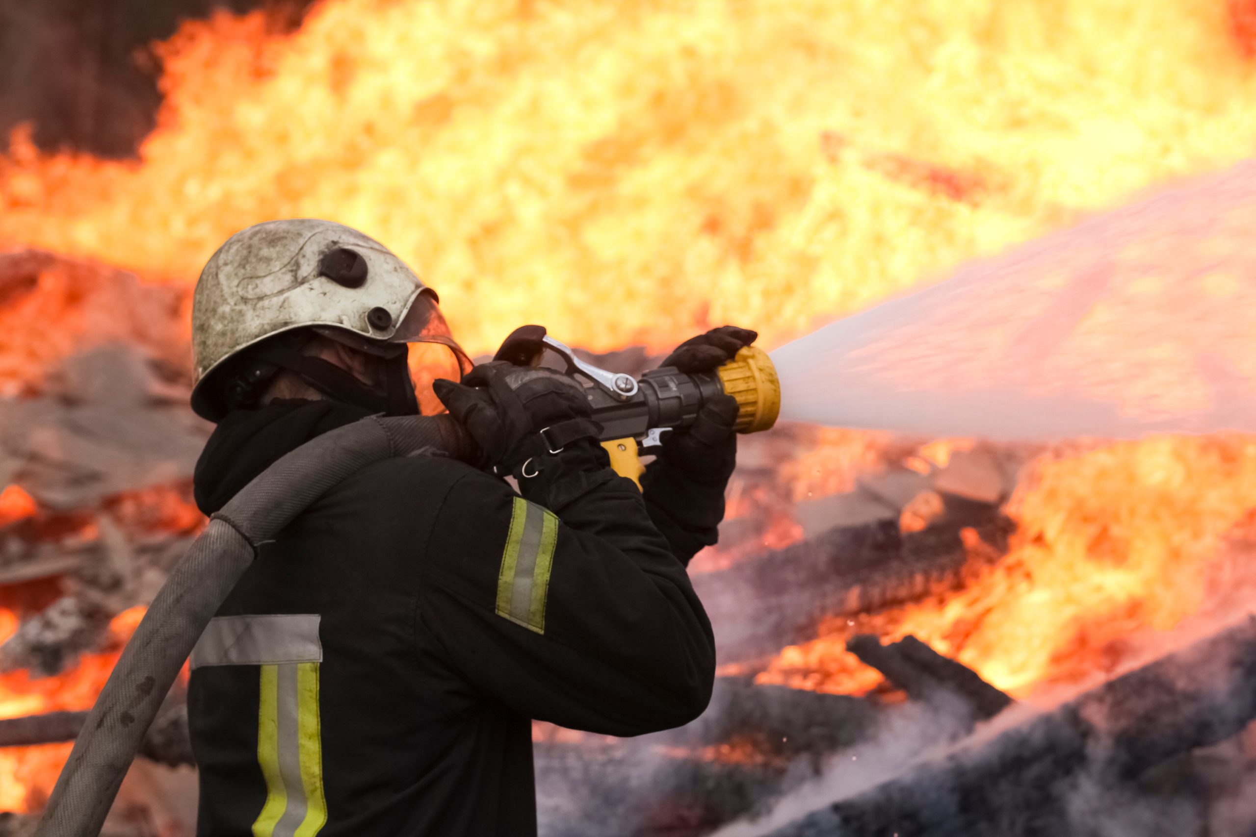 Firefighter extinguishing burning flames with hose